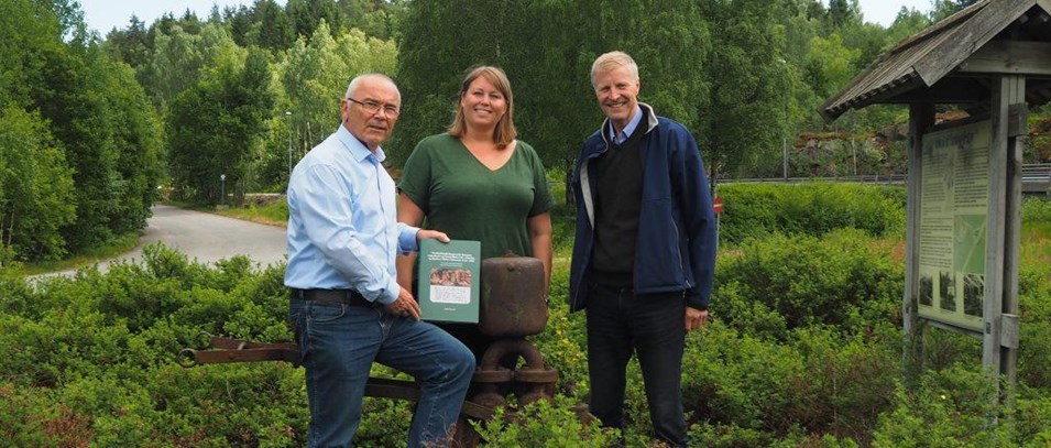 Forfatter Ingulv Burvald, kommunikasjonssjef Cathrine W. Eidal og bransjesjef Runar Rugtvedt ved en gammel pumpe brukt i den tidligere bergverksdriften. Forfatteren har selv trukket pumpa ut fra skogen!