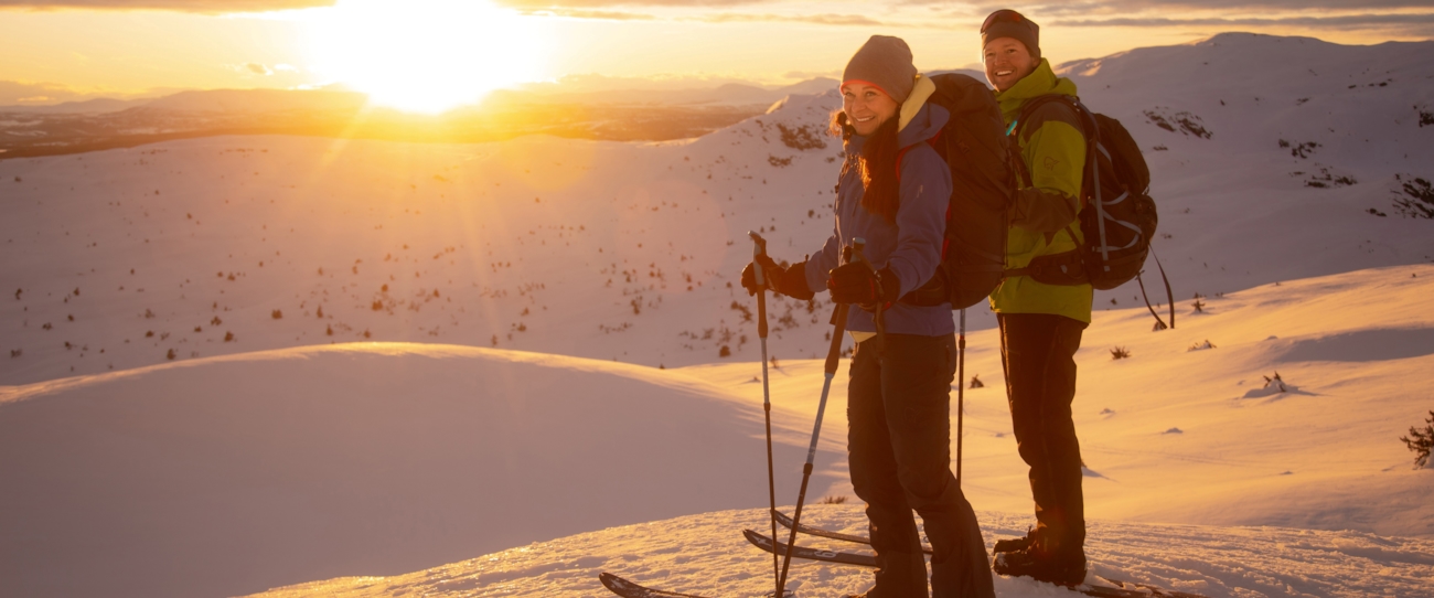 To personer på ski ser utover vinterlandskap