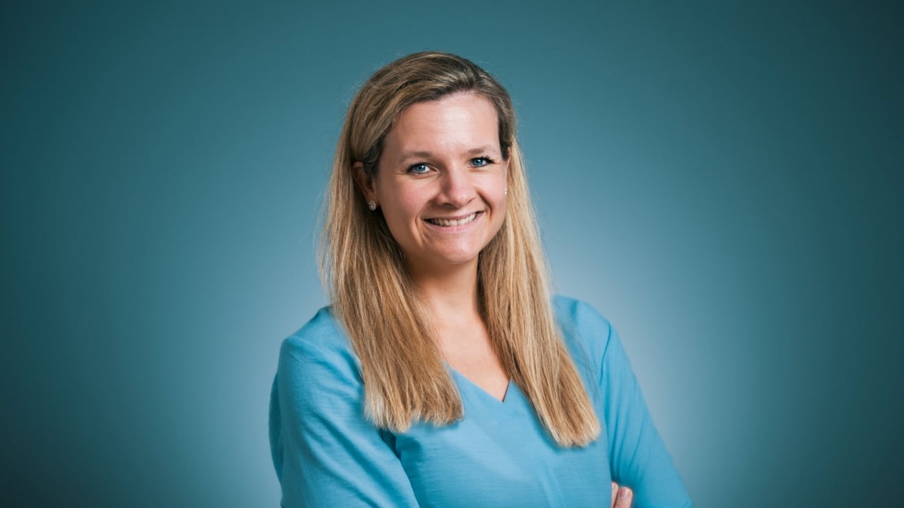 Smilende person foran blå bakgrunn