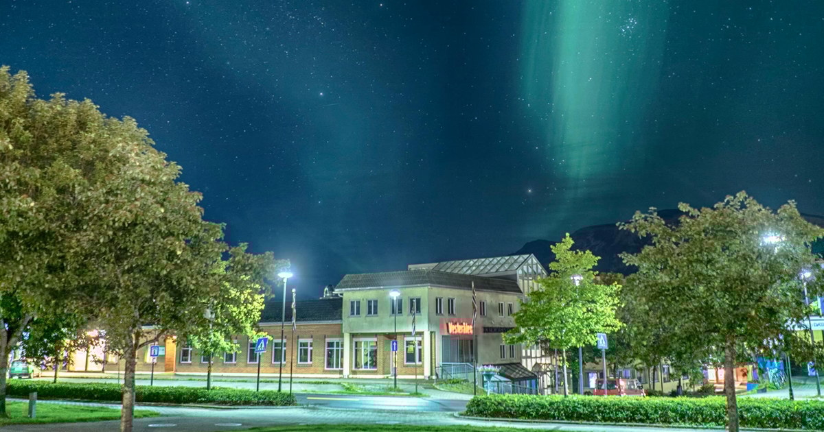 Bygning sett fra utsiden, nordlys på himmelen over bygget