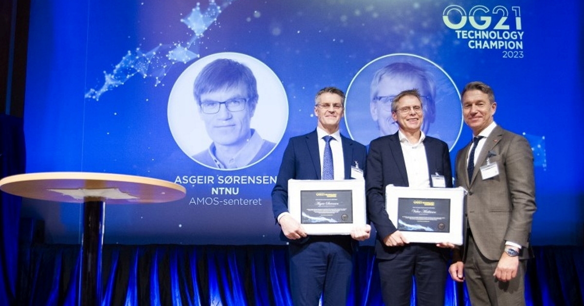 To personer som mottar en pris. Holder diplom forran seg på en scene,.