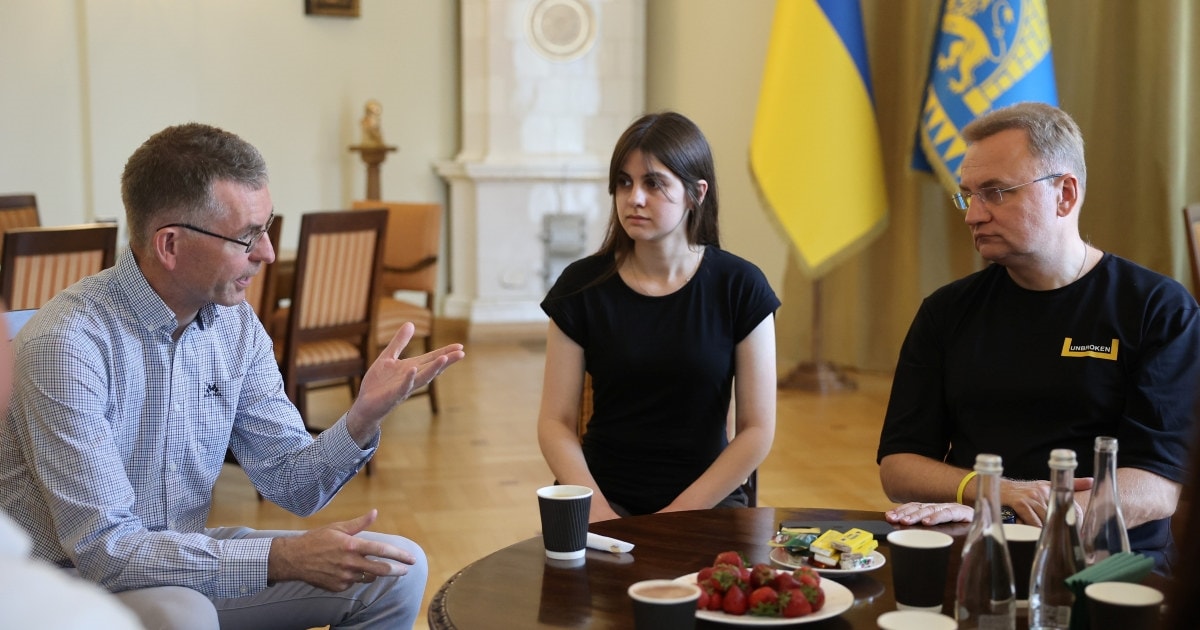 Tre personer rundt et bord diskuterer